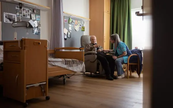 Verpleegkundige die op een stoel zit naast een man