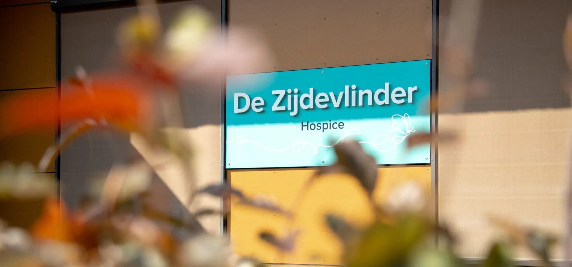 Bord met de tekst "De Zijdevlinder Hospice" op een muur