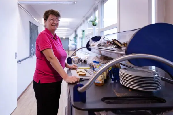 Vrouw die eter rondbrengt met een kar voor gerontopsychiatrisch verpleeghuis