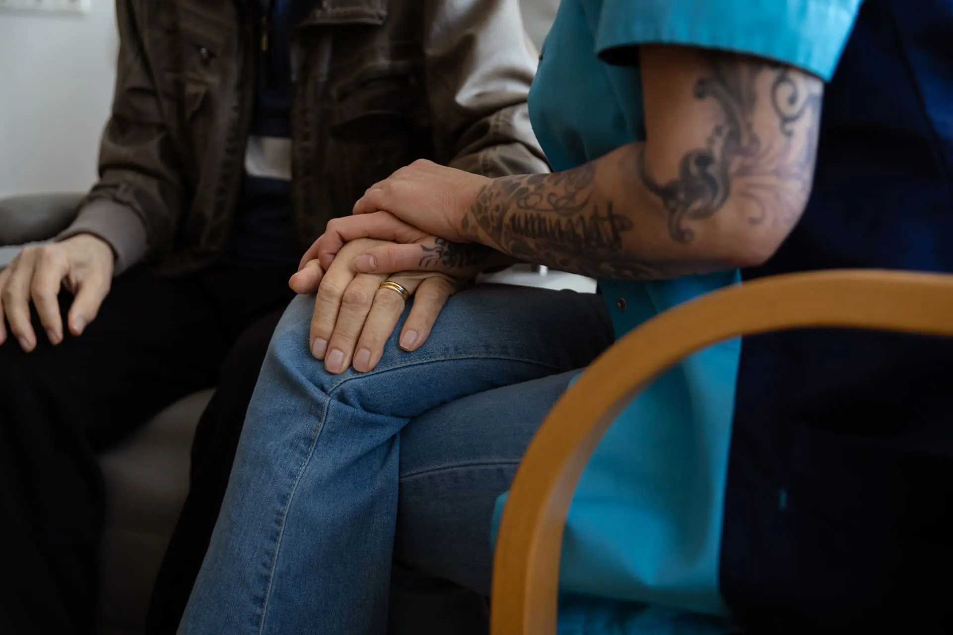 Vrouw die als vrijwilliger in een hospice haar hand op een andere hand heeft.