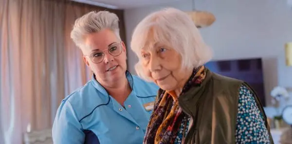 Verpleegkundige die een oudere vrouw aankijkt