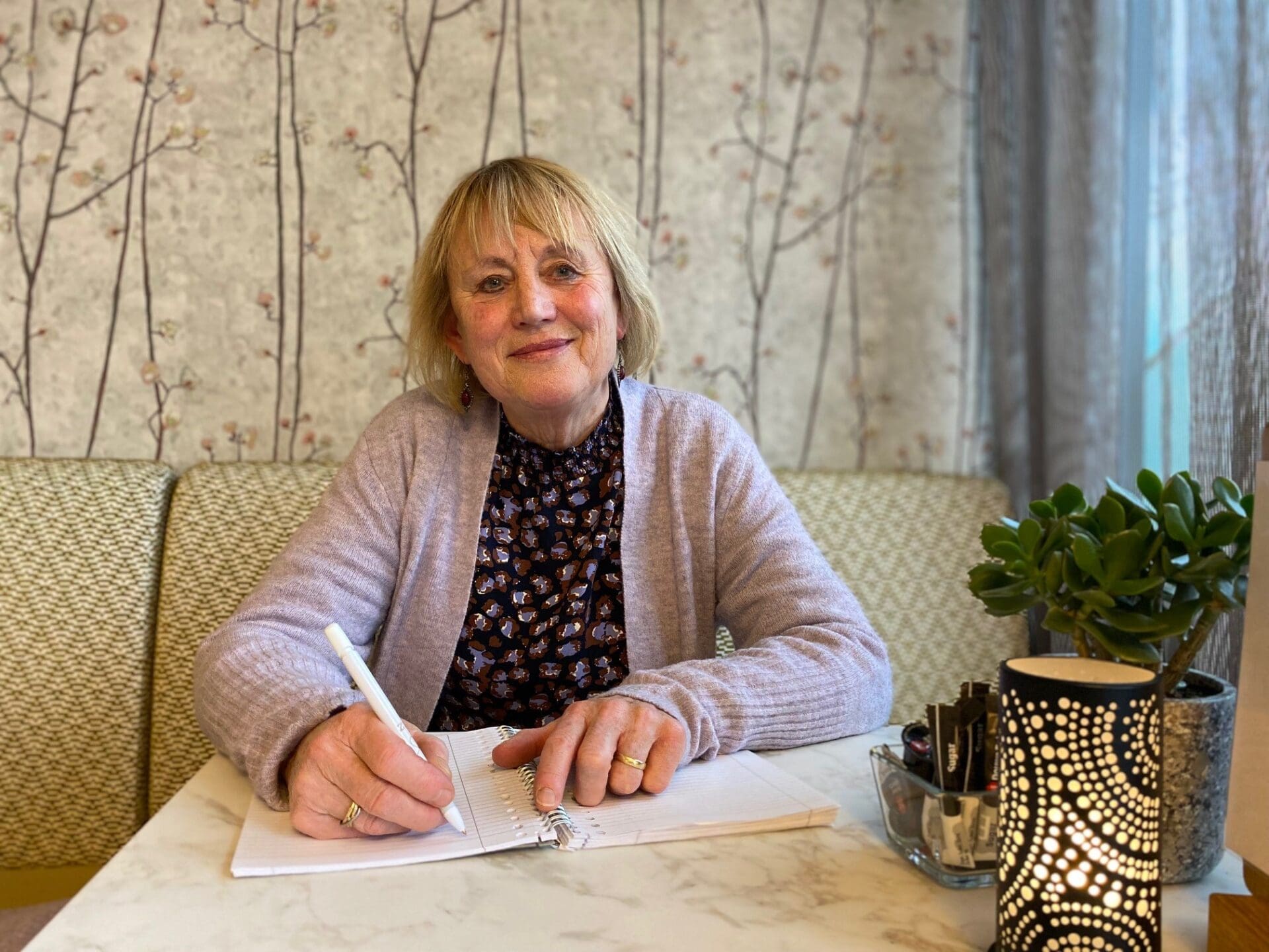 Riny die een pen vasthoudt en schrijft in een schrift