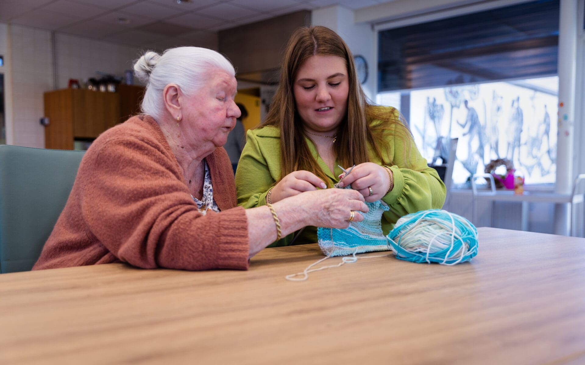Vrijwilliger en vrouw die samen aan het breien zijn
