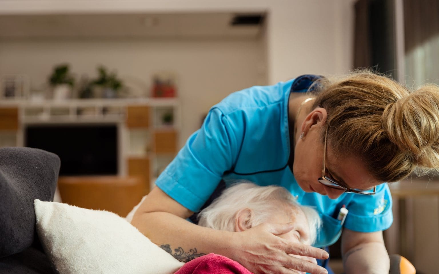 Verpleegkundige die haard hand op het gezicht van een patiënt legt - Hospicezorg vrijwilliger